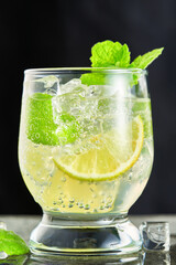 Close-up of one glass with a mojito cocktail on a grey background. Vertical shot from a low angle.