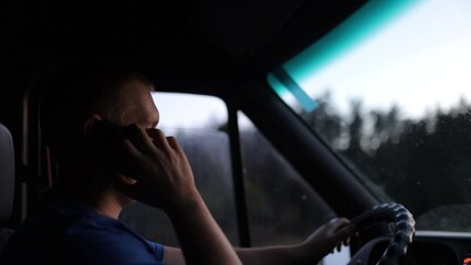 male truck driver uses smartphone on the road driving