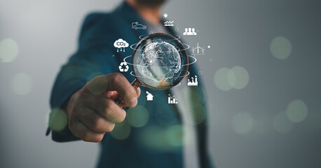 Businessman holding magnifying glass with environmental protection and energy saving icon for...