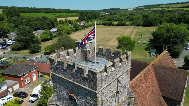A slow boom-shot of a union flag flying from the tower of St Mary's church in Chartham.