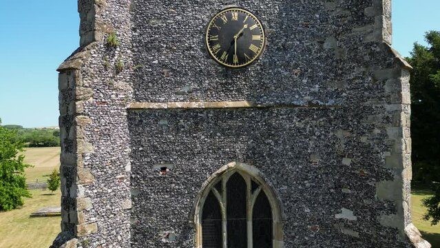 A crawling boom-shot of the tower of St Mary's church in Chartham, showing one of the large windows and clock.