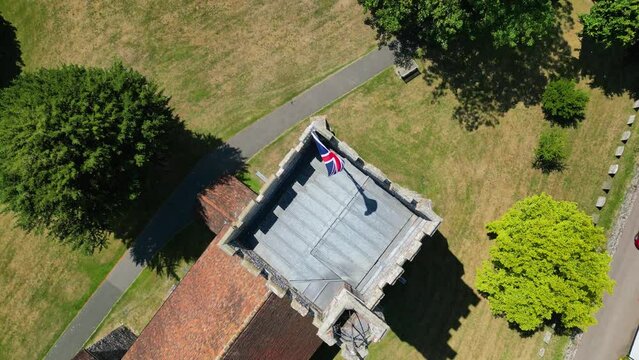 A top-down pan of a union flag flying from the tower of St Mary's church in Chartham.