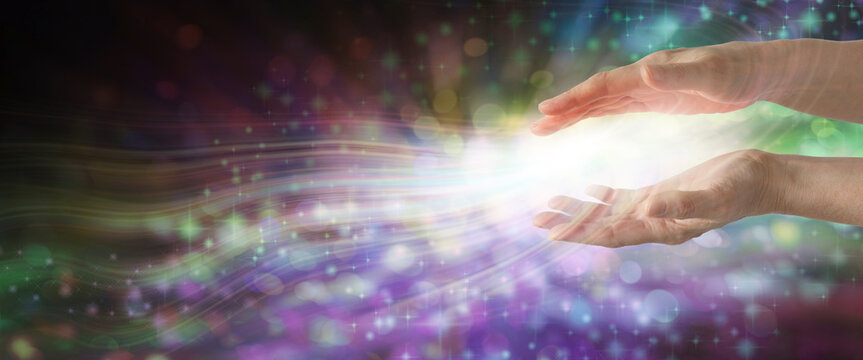 Magical Energy Healing Hands Sensing healing vibes - ethereal multi coloured background and female parallel hands sending out white light with copy space
