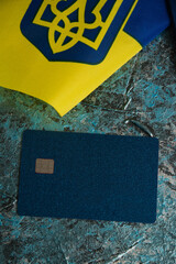 Modern bank card with chip close-up, flag of Ukraine and Ukrainian passport. The concept of departure of Ukrainians abroad.