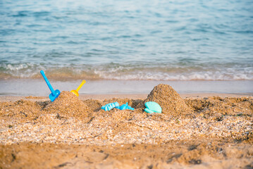 Fototapeta na wymiar Children's toys on a sandy beach, blue sea in the background