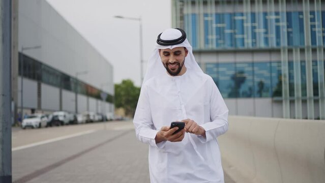 Handsome businessman with the traditional emirates white outfit working outdoor in Dubai city. Concept about middle eastern cultures and business