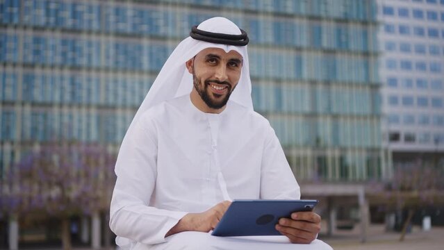 Handsome businessman with the traditional emirates white outfit working outdoor in Dubai city. Concept about middle eastern cultures and business