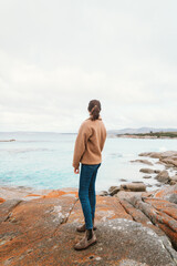Woman standing on Rocks at Bay of Fires near Suicide Beach via the Gardens Road, in Tasmania, North East Tasmania, Australia
