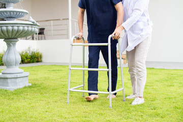 Patient using mobility walker in garden at sanatorium center - obrazy, fototapety, plakaty