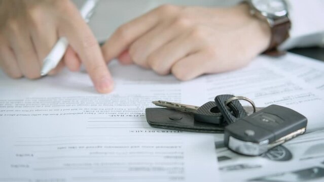 Buyers or sellers who are reading car lease or car insurance contract and signing. Sale agent deal to agreement car loan contract with customer and sign agreement contract, car Insurance concept.