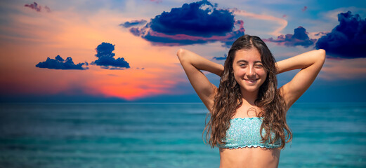 A beautiful girl at sunset enjoys the tropical beach