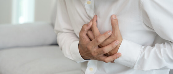 hand hold chest with heart attack symptoms, asian woman have chest pain caused by heart disease, leak, dilatation, enlarged coronary heart, press on the chest with a painful expression