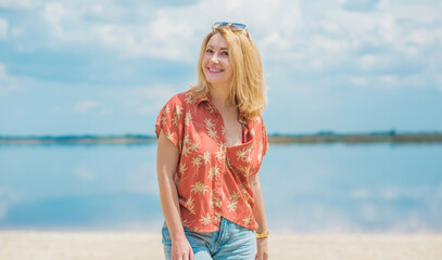 Fototapeta na wymiar Vacation style, woman wardrobe. Illustration of young European tanned woman with blonde hair in blue jeans and colorful cotton shirt at the beach