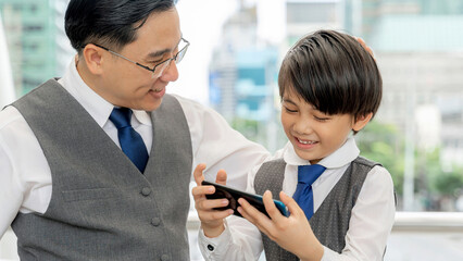 Father and son playing  smart phone together on business district urban, Dad and Son happy Asian...