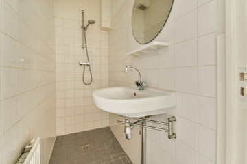 a bathroom with a sink, mirror and towel rack on the wall next to it is a white tiled floor