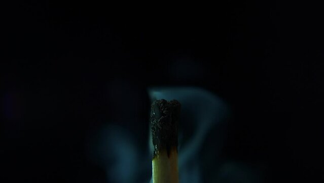 Blow match light flame with smoke. Close up burning match in hands in complete darkness, slow motion. Smoke from an extinguished match in pitch darkness. High quality 4k footage