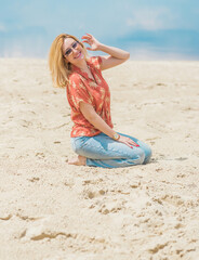 Vacation style, woman wardrobe. Illustration of young European tanned woman with blonde hair in blue jeans and colorful cotton shirt at the beach