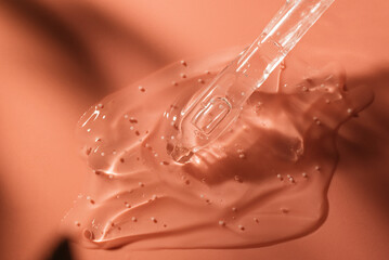 Beauty face serum gel with dropper. Transparent skincare cream with bubbles on coral background.