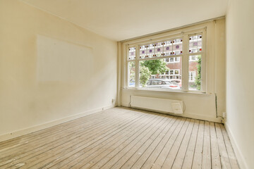 an empty room with white walls and wood flooring in front of a large window looking out onto the street