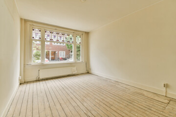 an empty room with white walls and wood flooring in front of a large window looking out onto the street