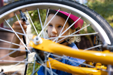 girl using air pump to inflate bicycle tire outdoors. bike maintenance