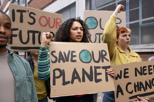 Young adult female protester raising her fist up at a climate change protest