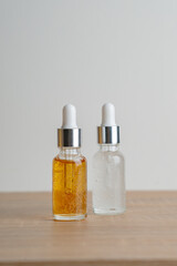 Amber glass bottles with dropper pipette with serum or essential oil on wood background.