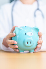 Doctor holding piggy bank and putting coin. and Healthcare cost, Money Saving, Health Insurance, Medical, Donation and Financial concepts