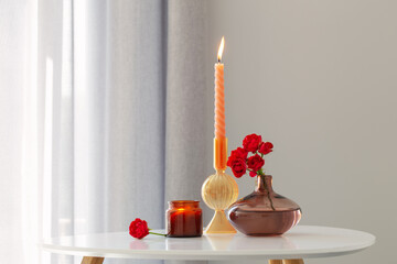 red roses in  vase with burning candles in white interior
