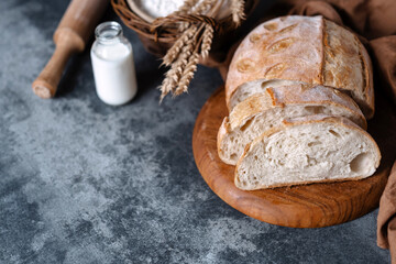 Slices of French bun on a wooden board on a table with ingredients. Whole grain white bread....