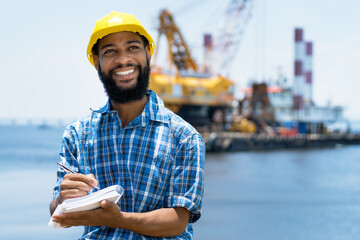 African american offshore worker with digger and plattform and ship at blue ocean