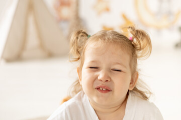 close-up portrait little child girl blond with blue eyes smiling in the children's room