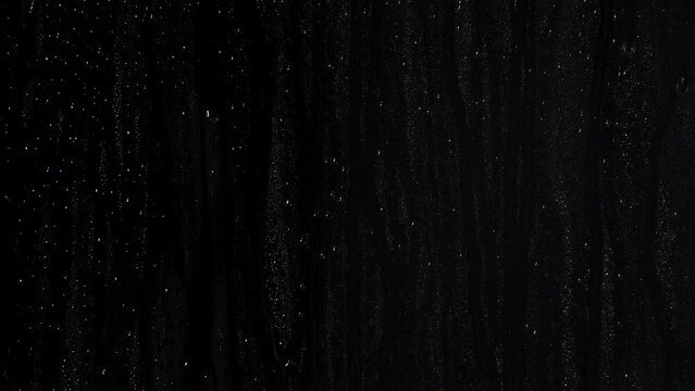 Water drops running with medium speed on a smooth surface with a black background  with a black background