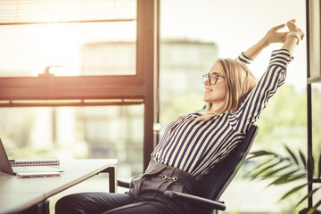 End of working day. Relax in the office in the glow of the setting sun. Happy woman office worker.