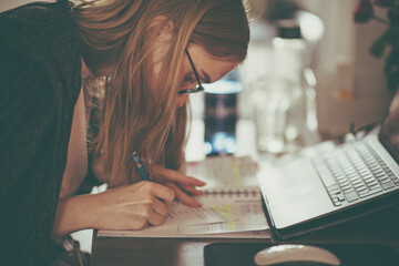 A focused girl takes notes during the home office.