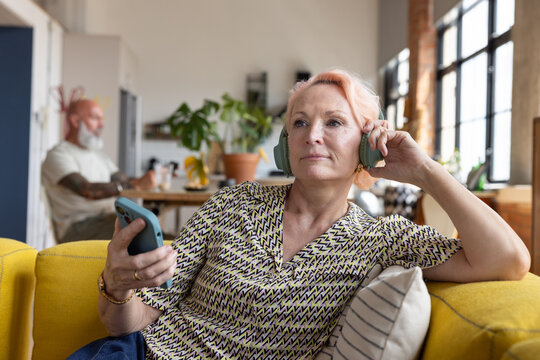 Fashionable senior woman at home elearning using a smartphone with headphones