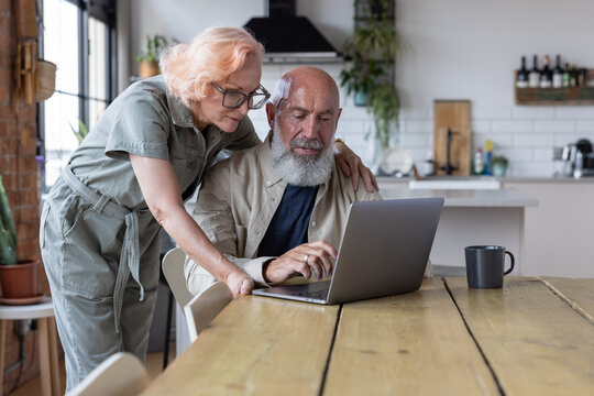 Senior couple at home looking at bills and personal finances using a laptop