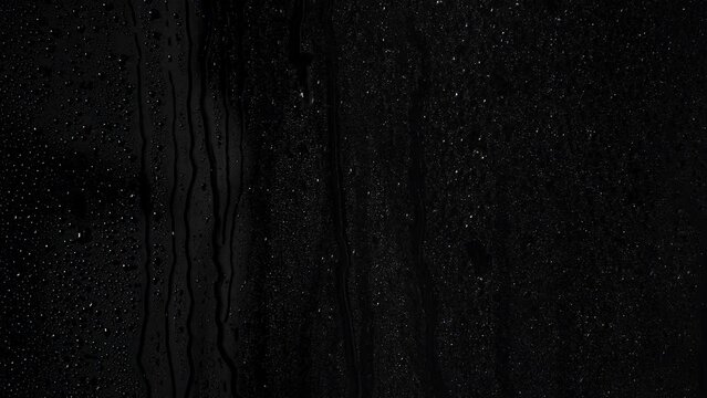 Rain on a window closeup with a black background