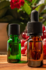 Brown and green bottles of essential oils. natural cosmetics for skin care. Bottles with an eyedropper, grapes and flowers on a wooden table. Taking care of health and beauty.