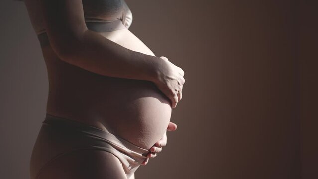 pregnant woman. health pregnancy motherhood procreation concept. close-up belly of a pregnant woman. woman waiting for indoors a newborn baby. pregnant woman holding her belly sunlight