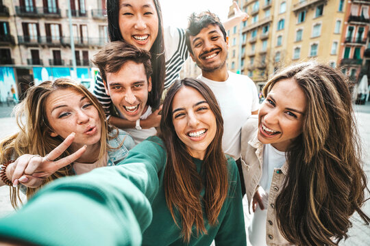Happy multiracial friends taking selfie pic with smart mobile phone device outside - Group of young people laughing walking together on city street - Life style concept with guys and girls hanging out