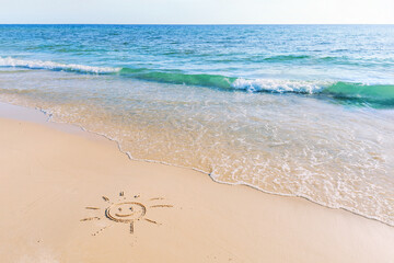 Fototapeta na wymiar The drawing of the sun on sand beach with soft waves