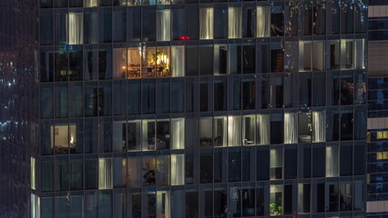 Frontal view of night facade of building with a lot of windows with light timelapse.