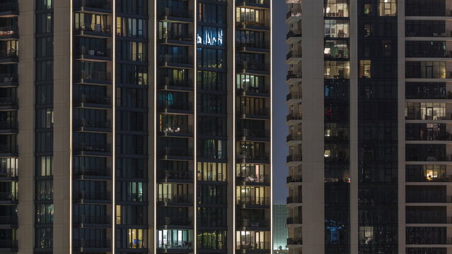 Tall blocks of flats with glowing windows located in residential district of city aerial timelapse.
