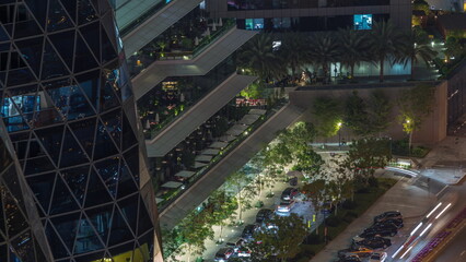 Aerial looking down view of cozy restaurants in the open air terrace of skyscraper night timelapse.