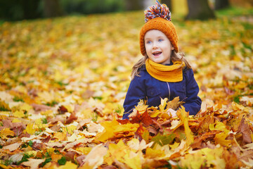 Adorable preschooler girl enjoying nice and sunny autumn day outdoors