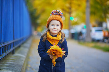 Adorable preschooler girl enjoying nice and sunny autumn day outdoors