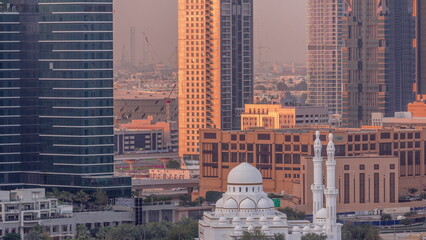 New white mosque near bay avenue surrounded by skyscrapers in Business Bay district aerial timelapse.