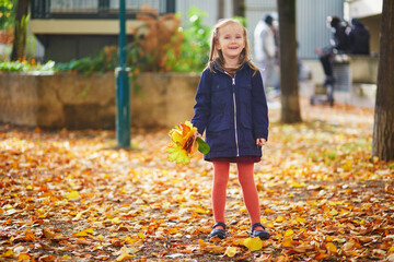 Adorable preschooler girl enjoying nice and sunny autumn day outdoors