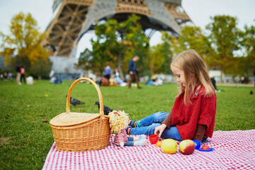 Adorable preschooler girl having picnic near the Eiffel tower in Paris, France
